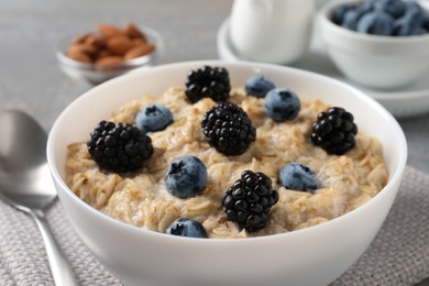Tasty oatmeal porridge with blackberries and blueberries in bowl on table, closeup Photo of Tasty oatmeal porridge with blackberries and blueberries in bowl on table, closeup