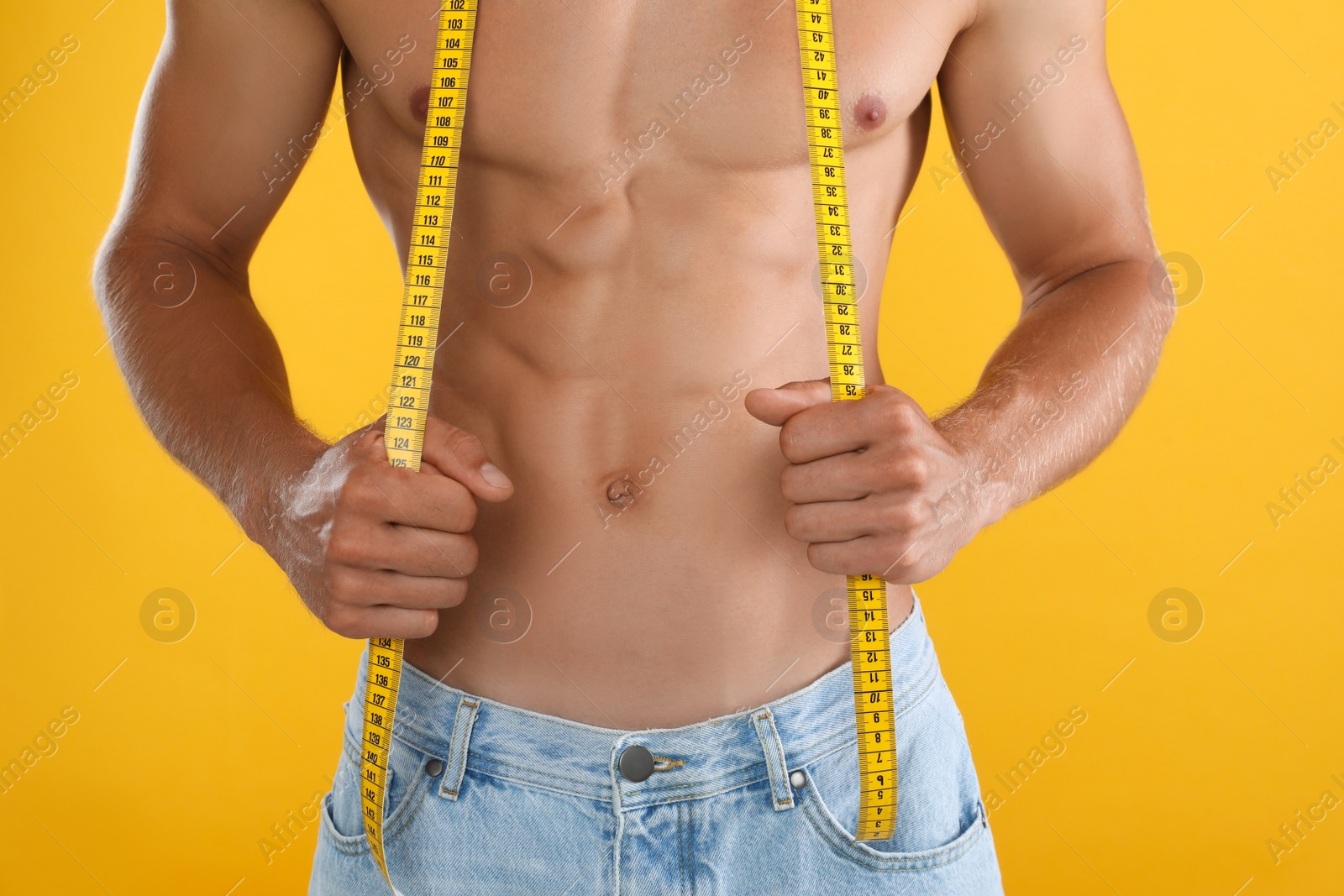 Shirtless man with slim body and measuring tape on yellow background, closeup Photo of Shirtless man with slim body and measuring tape on yellow background, closeup