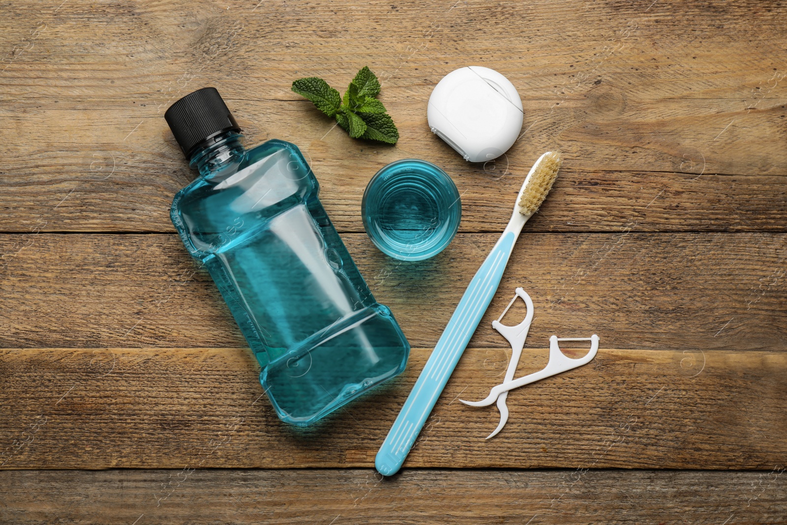 Flat lay composition with mouthwash and other oral hygiene products on wooden table Photo of Flat lay composition with mouthwash and other oral hygiene products on wooden table
