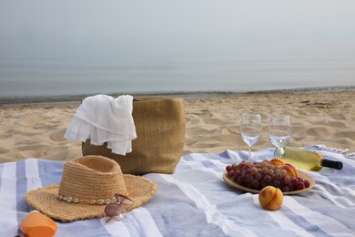 Bag, blanket, wine and other stuff for beach picnic on sandy seashore Photo of Bag, blanket, wine and other stuff for beach picnic on sandy seashore