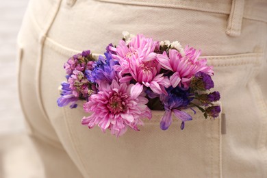 Woman wearing jeans with flowers in pocket, closeup Photo of Woman wearing jeans with flowers in pocket, closeup