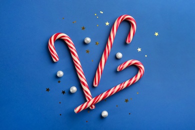 Candy canes on blue background, flat lay. Christmas treat Photo of Candy canes on blue background, flat lay. Christmas treat