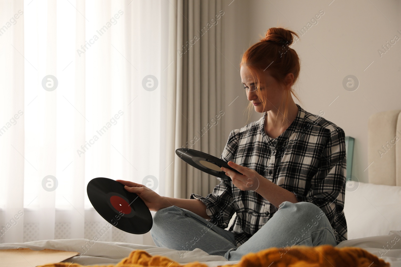 Young woman choosing vinyl disc to play music with turntable in bedroom Photo of Young woman choosing vinyl disc to play music with turntable in bedroom