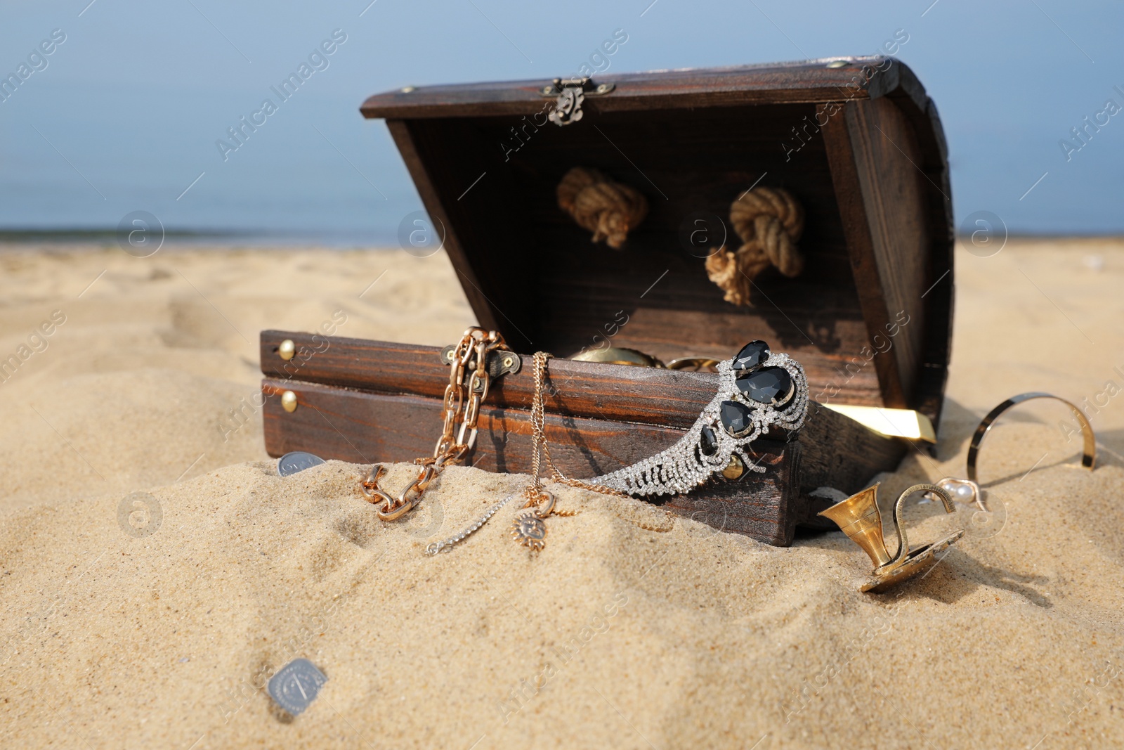 Open wooden treasure chest on sandy beach Photo of Open wooden treasure chest on sandy beach