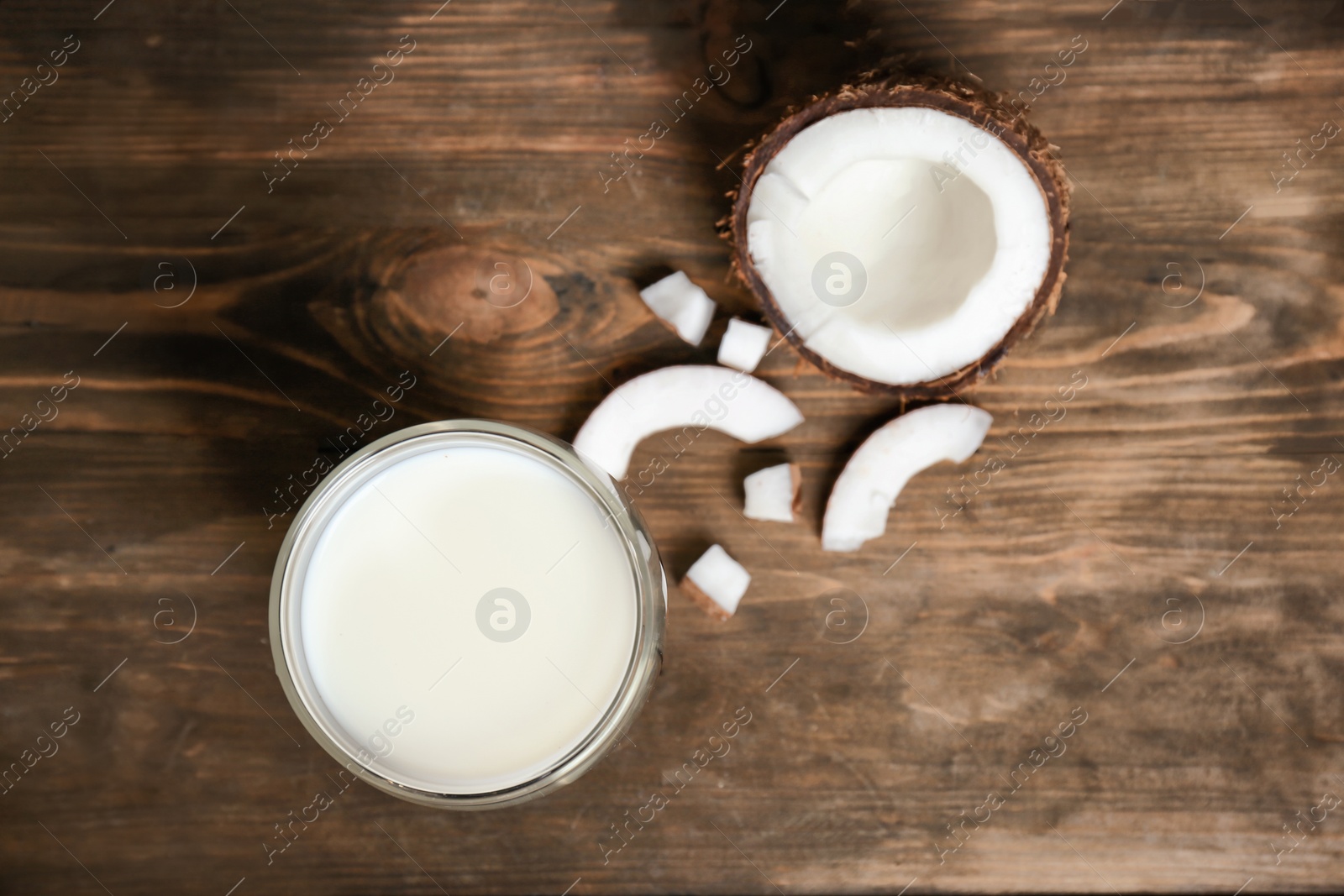 Glass of coconut milk and fresh nut on wooden background, top view Photo of Glass of coconut milk and fresh nut on wooden background, top view