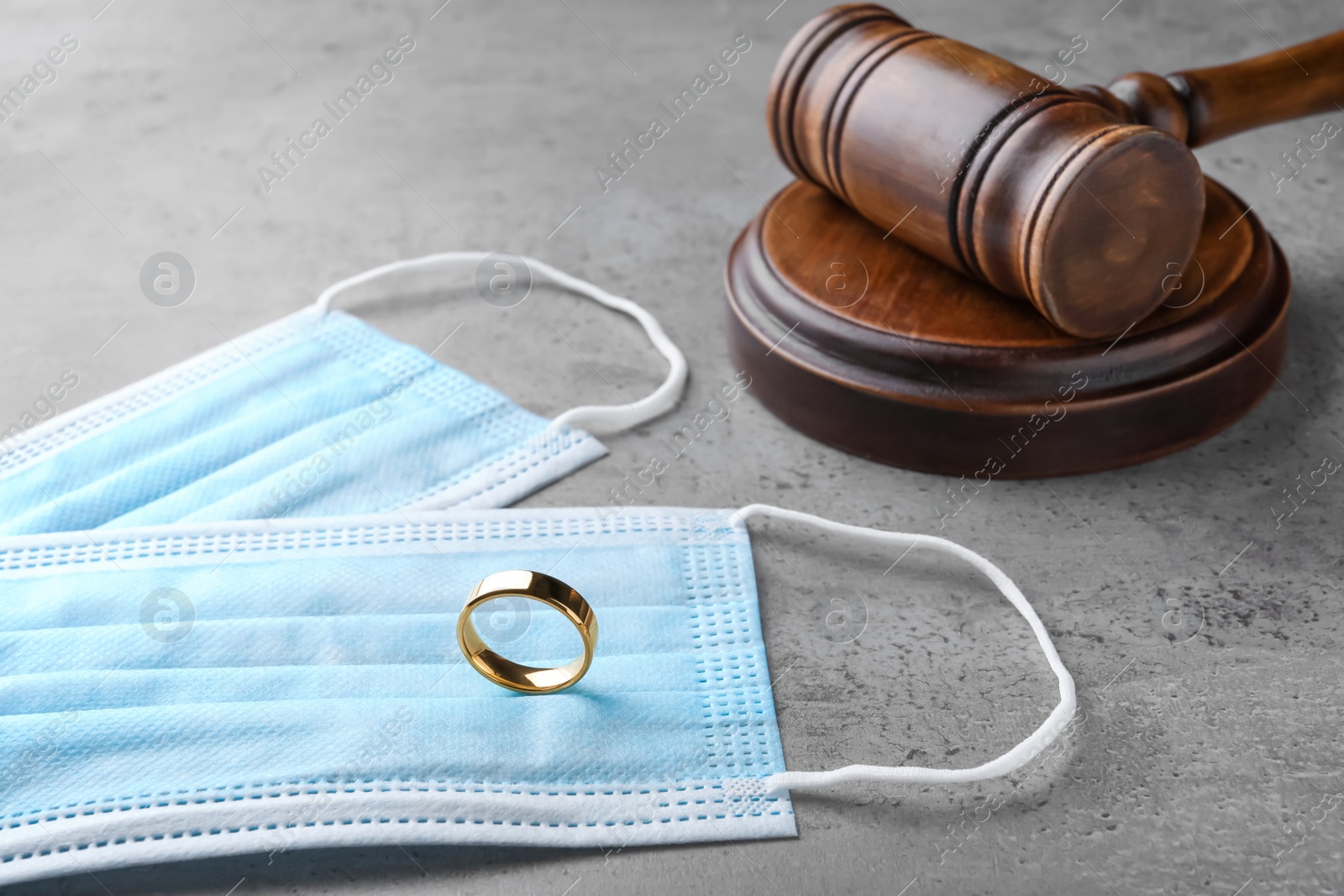 Gavel, protective masks and wedding ring on grey table. Divorce during coronavirus quarantine Photo of Gavel, protective masks and wedding ring on grey table. Divorce during coronavirus quarantine