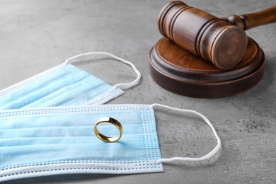 Gavel, protective masks and wedding ring on grey table. Divorce during coronavirus quarantine Photo of Gavel, protective masks and wedding ring on grey table. Divorce during coronavirus quarantine