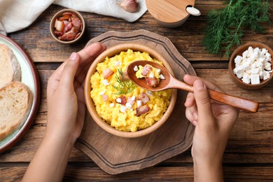 Woman eating banosh with brynza and pork cracklings at wooden table, top view. Traditional Ukrainian dish Photo of Woman eating banosh with brynza and pork cracklings at wooden table, top view. Traditional Ukrainian dish