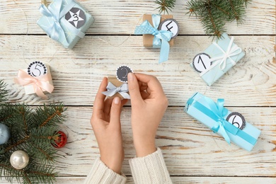 Woman making advent calendar at white wooden table, top view Photo of Woman making advent calendar at white wooden table, top view