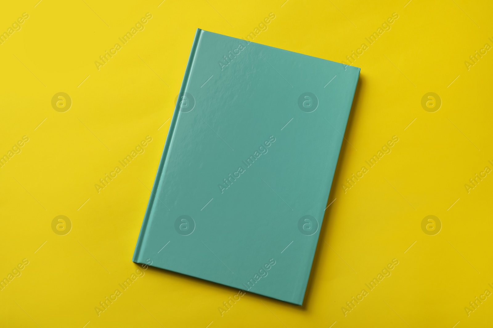 New stylish planner with hard cover on yellow background, top view Photo of New stylish planner with hard cover on yellow background, top view