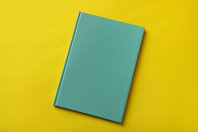 New stylish planner with hard cover on yellow background, top view Photo of New stylish planner with hard cover on yellow background, top view