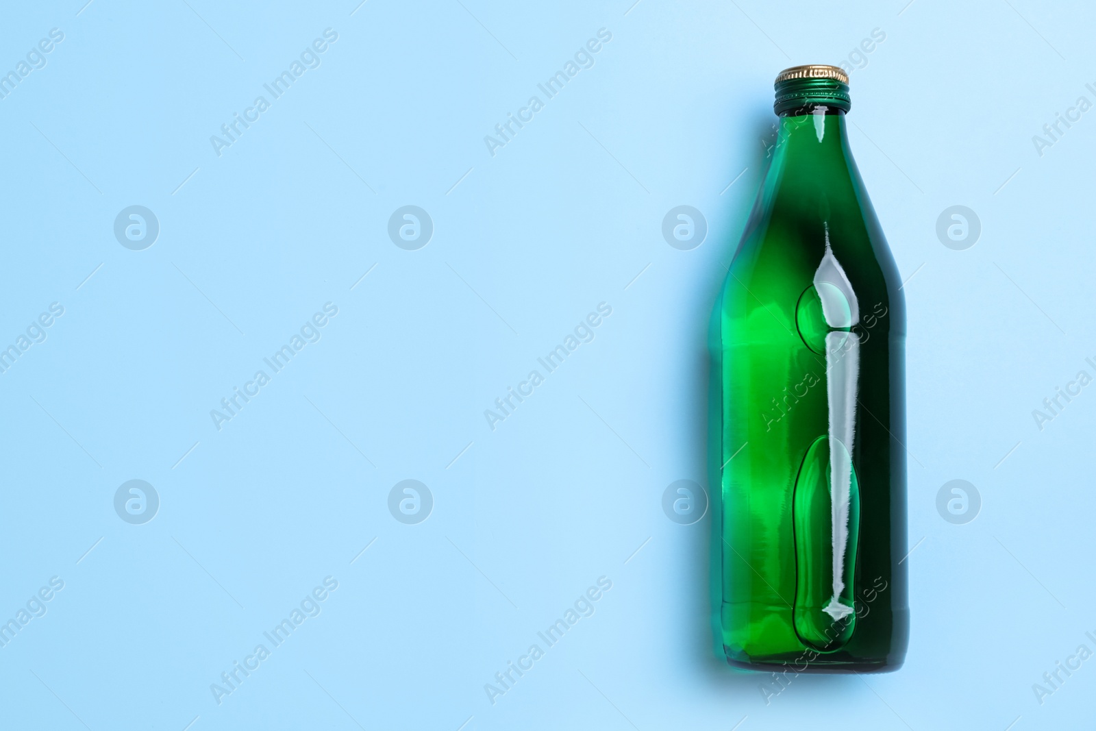 Glass bottle with water on light blue background, top view. Space for text Photo of Glass bottle with water on light blue background, top view. Space for text