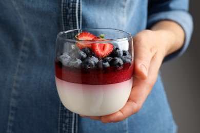 Woman holding glass dish delicious panna cotta with berries, closeup Photo of Woman holding glass dish delicious panna cotta with berries, closeup