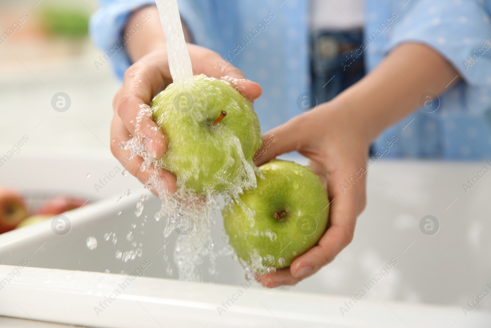 Woman washing fresh green apples in kitchen sink, closeup Photo of Woman washing fresh green apples in kitchen sink, closeup