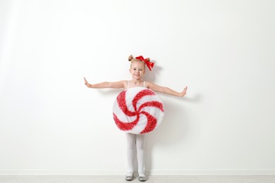 Cute little girl dressed as candy near white wall. Christmas suit Image of Cute little girl dressed as candy near white wall. Christmas suit