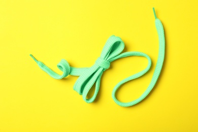 Green shoelace on yellow background, top view Photo of Green shoelace on yellow background, top view