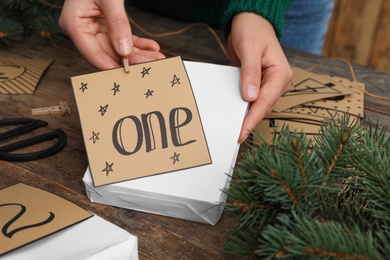 Woman making advent calendar at wooden table, closeup Photo of Woman making advent calendar at wooden table, closeup