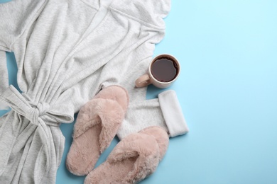 Fluffy slippers, robe and cup of coffee on light blue background, flat lay. Comfortable home outfit Photo of Fluffy slippers, robe and cup of coffee on light blue background, flat lay. Comfortable home outfit