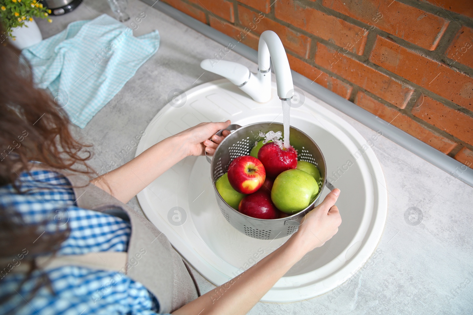 Young woman washing ripe apples in kitchen Photo of Young woman washing ripe apples in kitchen