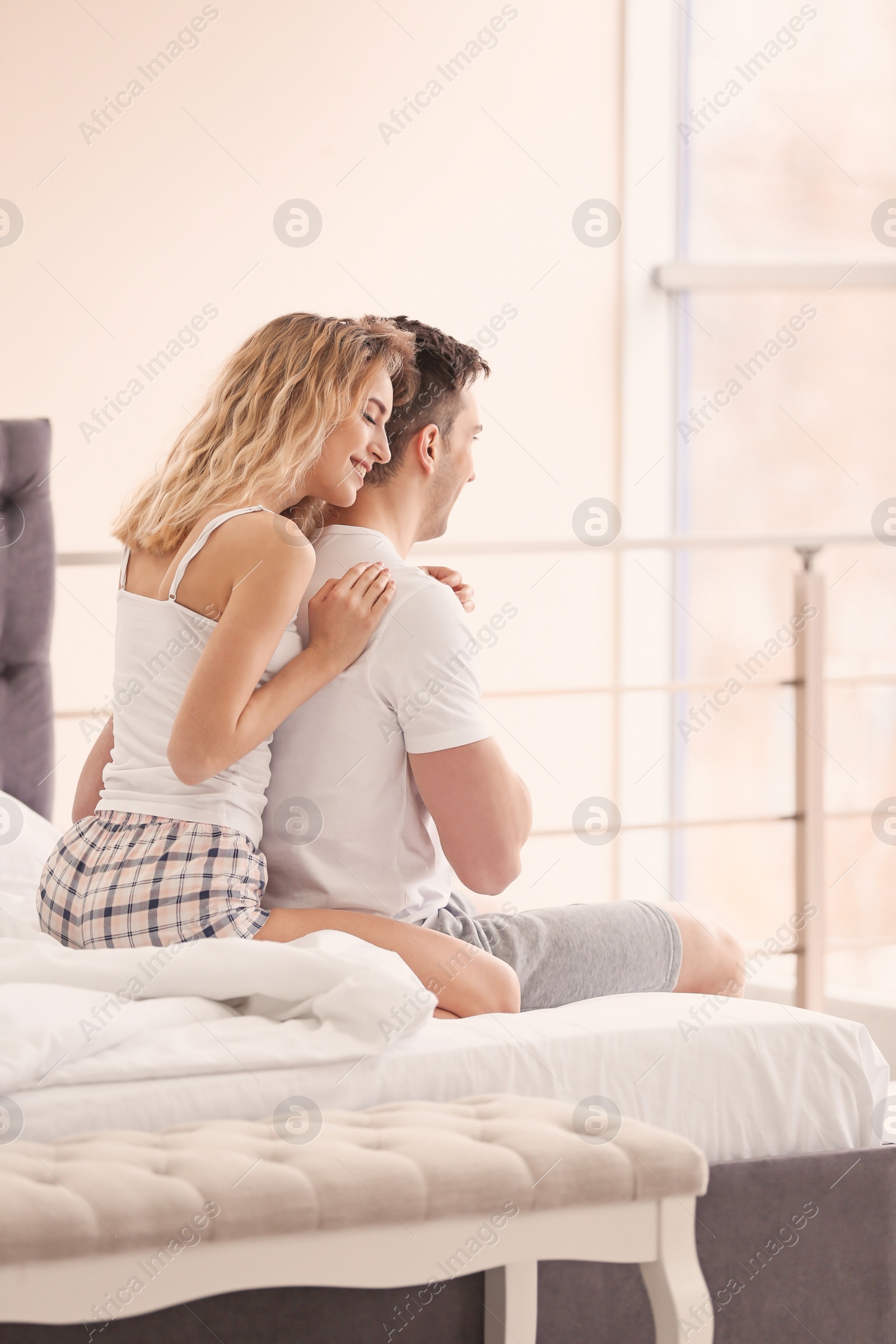 Photo of Young couple hugging on bed at home