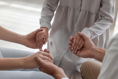 Group of religious people holding hands and praying together indoors, closeup Photo of Group of religious people holding hands and praying together indoors, closeup