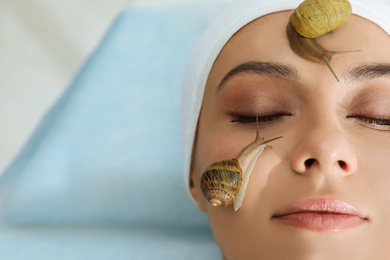 Young woman receiving snail facial massage in spa salon, closeup. Space for text Photo of Young woman receiving snail facial massage in spa salon, closeup. Space for text