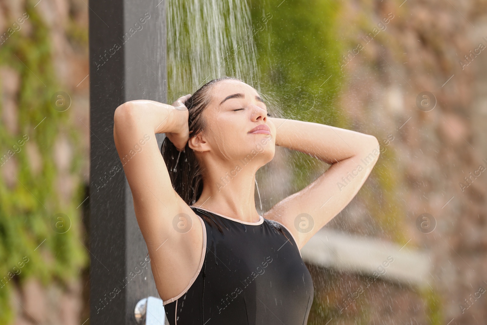 Woman washing hair in outdoor shower on summer day Photo of Woman washing hair in outdoor shower on summer day