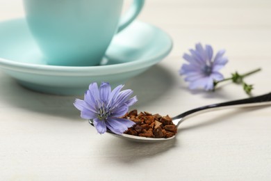 Spoon of chicory granules with flower on white wooden table, closeup Photo of Spoon of chicory granules with flower on white wooden table, closeup