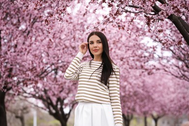 Pretty young woman in park with blooming trees. Spring look Photo of Pretty young woman in park with blooming trees. Spring look
