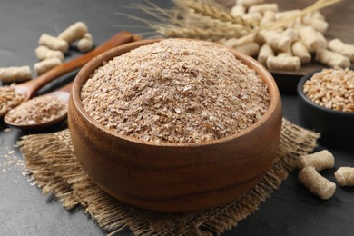 Wheat bran in bowl on black table Photo of Wheat bran in bowl on black table