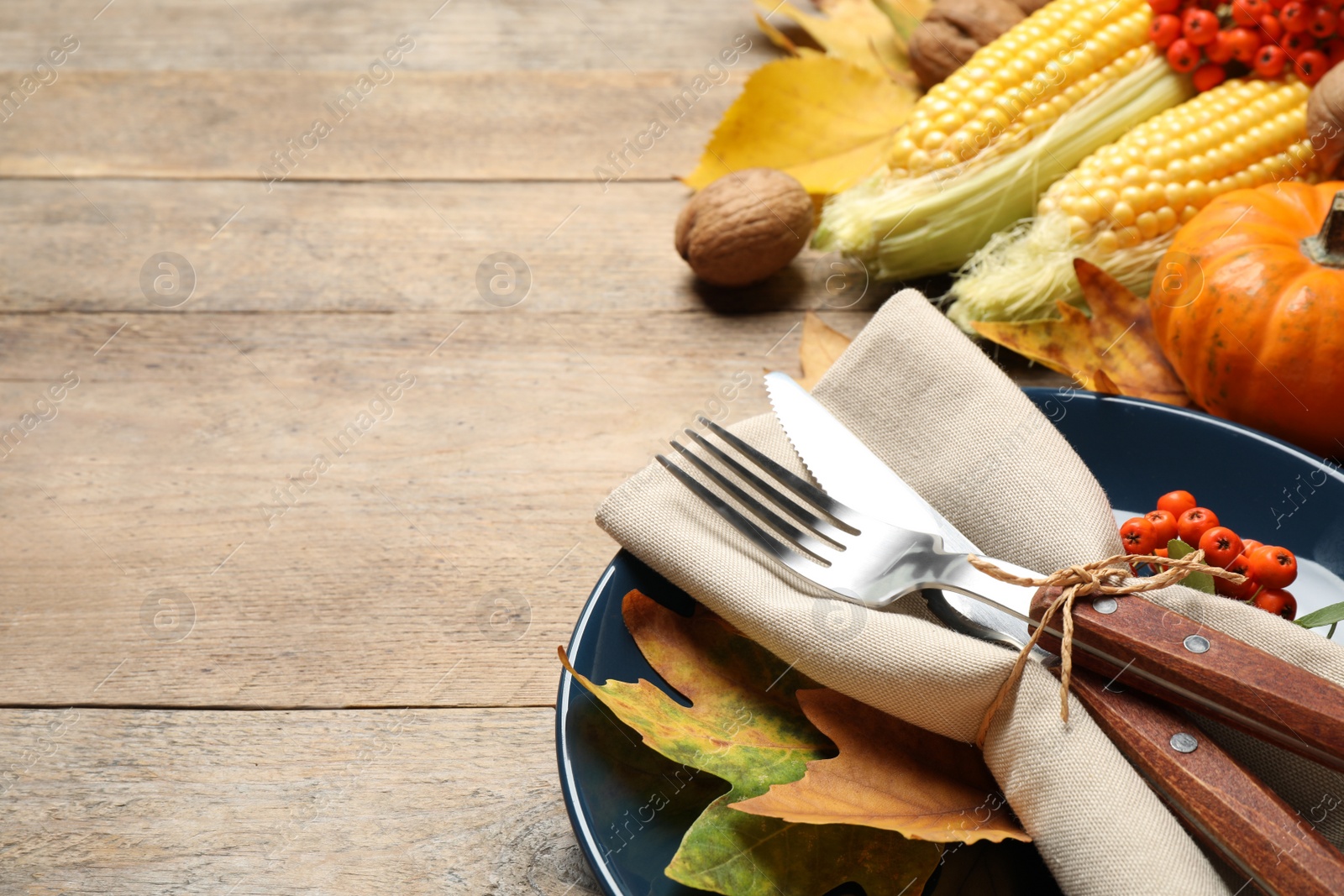 Seasonal table setting with autumn leaves and vegetables on wooden background, space for text. Thanksgiving Day Photo of Seasonal table setting with autumn leaves and vegetables on wooden background, space for text. Thanksgiving Day