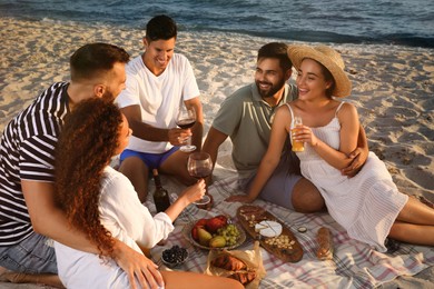 Group of friends having picnic on sandy beach near sea Photo of Group of friends having picnic on sandy beach near sea