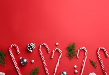 Flat lay composition with candy canes and Christmas decor on red background. Space for text Photo of Flat lay composition with candy canes and Christmas decor on red background. Space for text