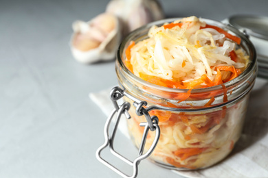 Photo of Tasty fermented cabbage with carrot on light grey table, closeup