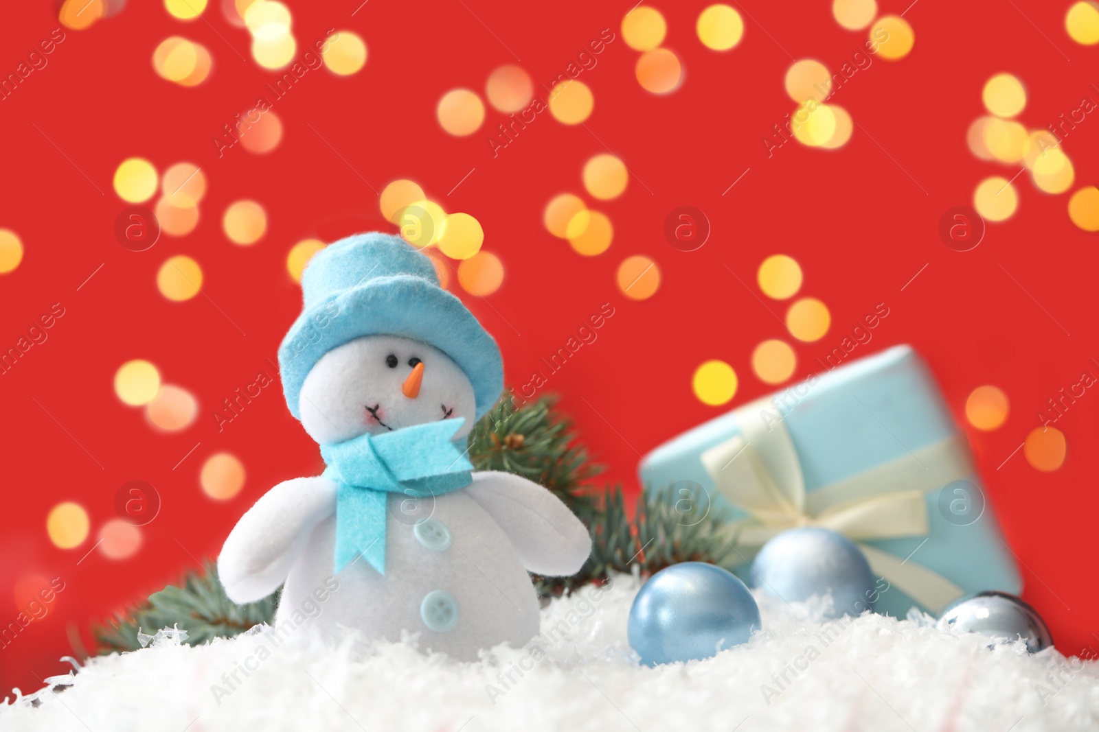 Snowman toy and Christmas balls on snow against blurred festive lights Photo of Snowman toy and Christmas balls on snow against blurred festive lights