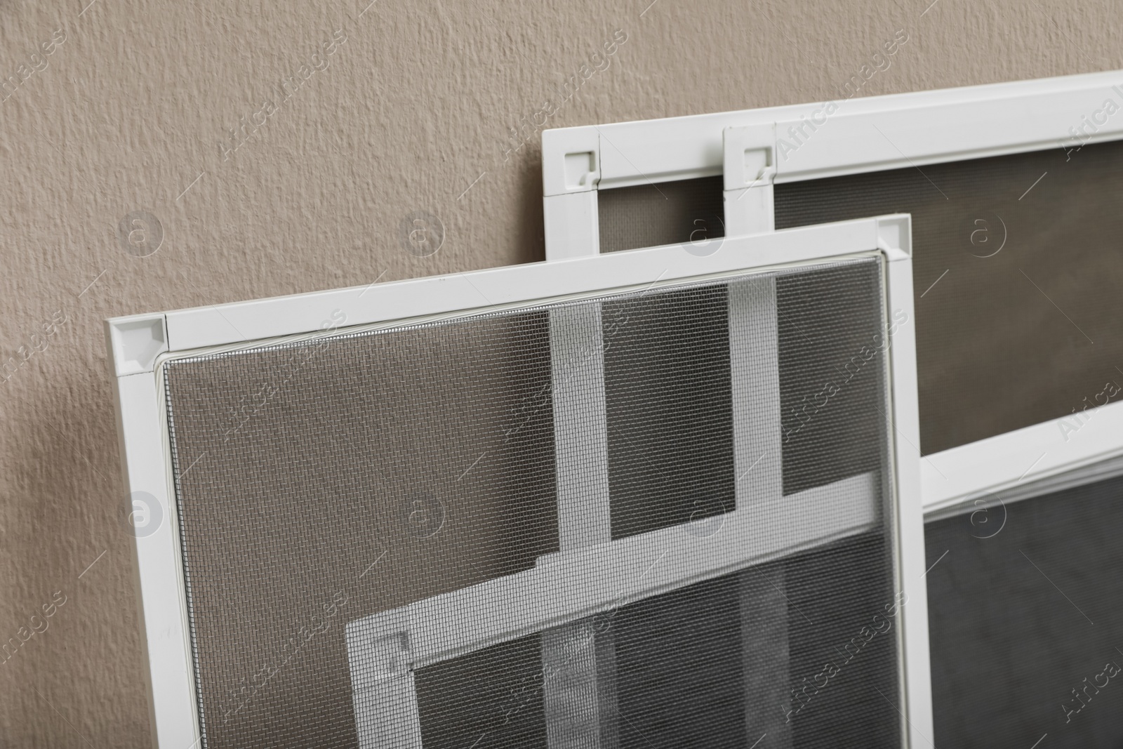 Photo of Set of window screens near beige wall, closeup