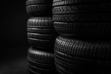 Stacked car tires on black background, closeup Photo of Stacked car tires on black background, closeup