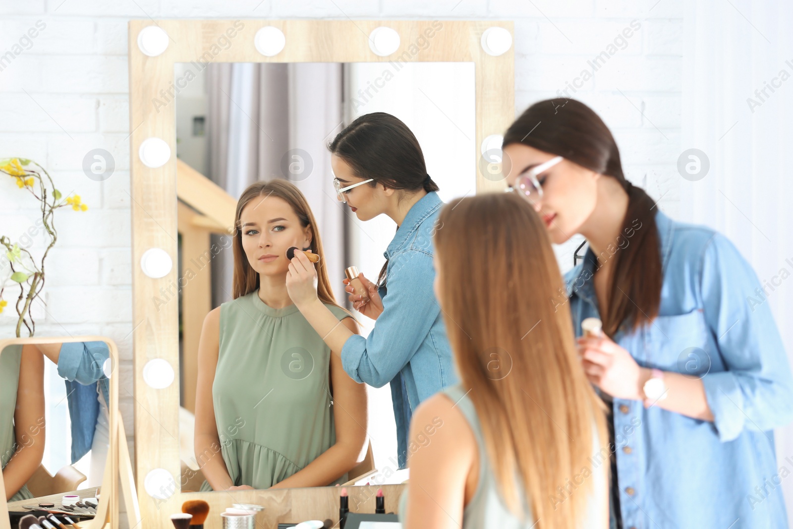 Professional visage artist applying makeup on woman's face in salon Photo of Professional visage artist applying makeup on woman's face in salon