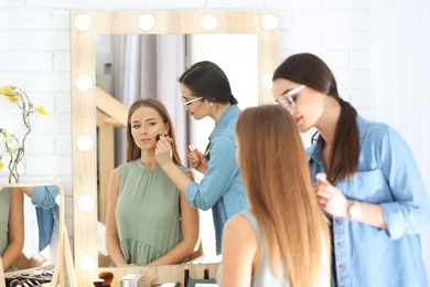 Professional visage artist applying makeup on woman's face in salon Photo of Professional visage artist applying makeup on woman's face in salon