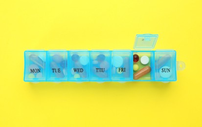 Pill box with medicaments on yellow background, top view Photo of Pill box with medicaments on yellow background, top view