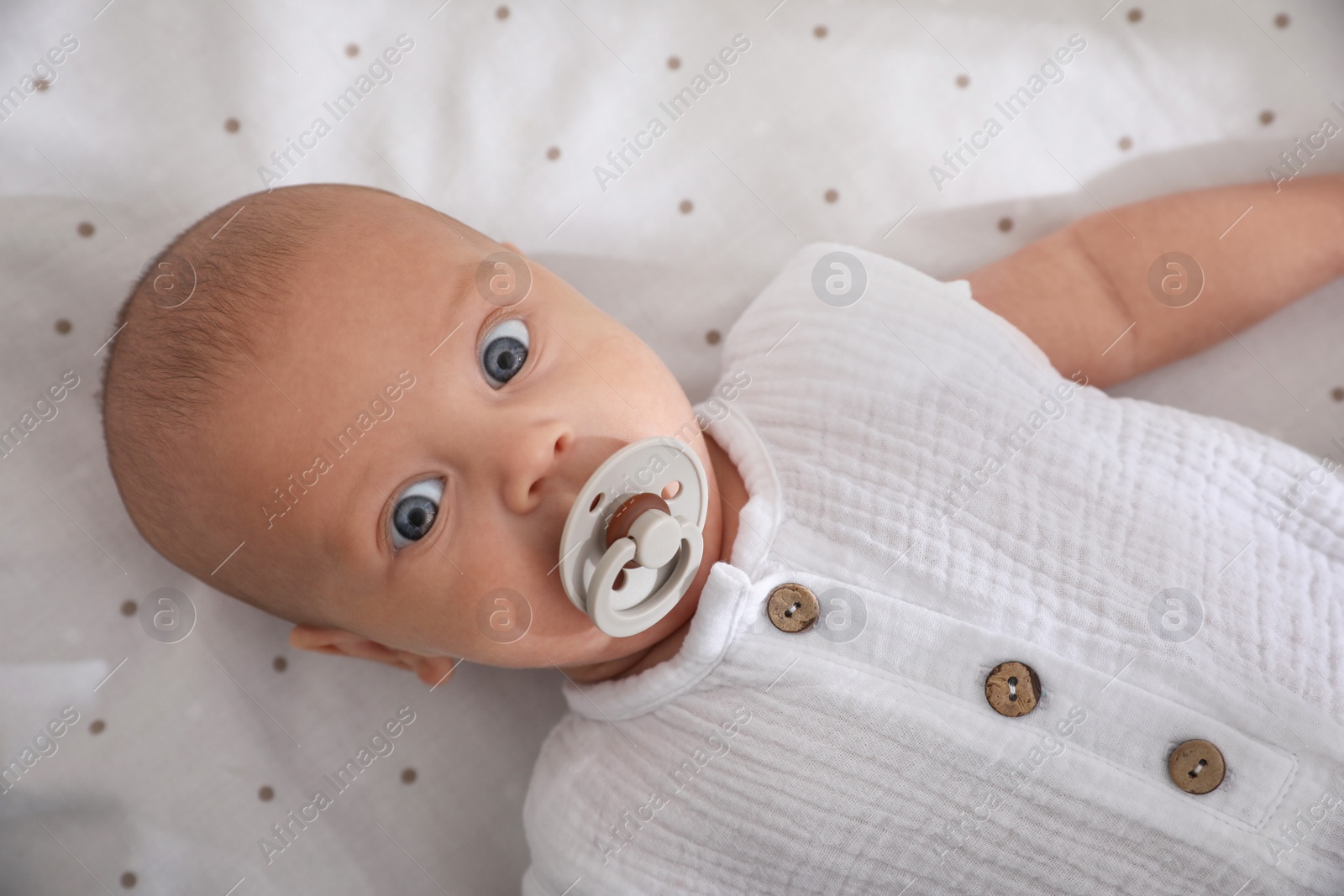 Cute little baby with pacifier lying on bed, top view Photo of Cute little baby with pacifier lying on bed, top view