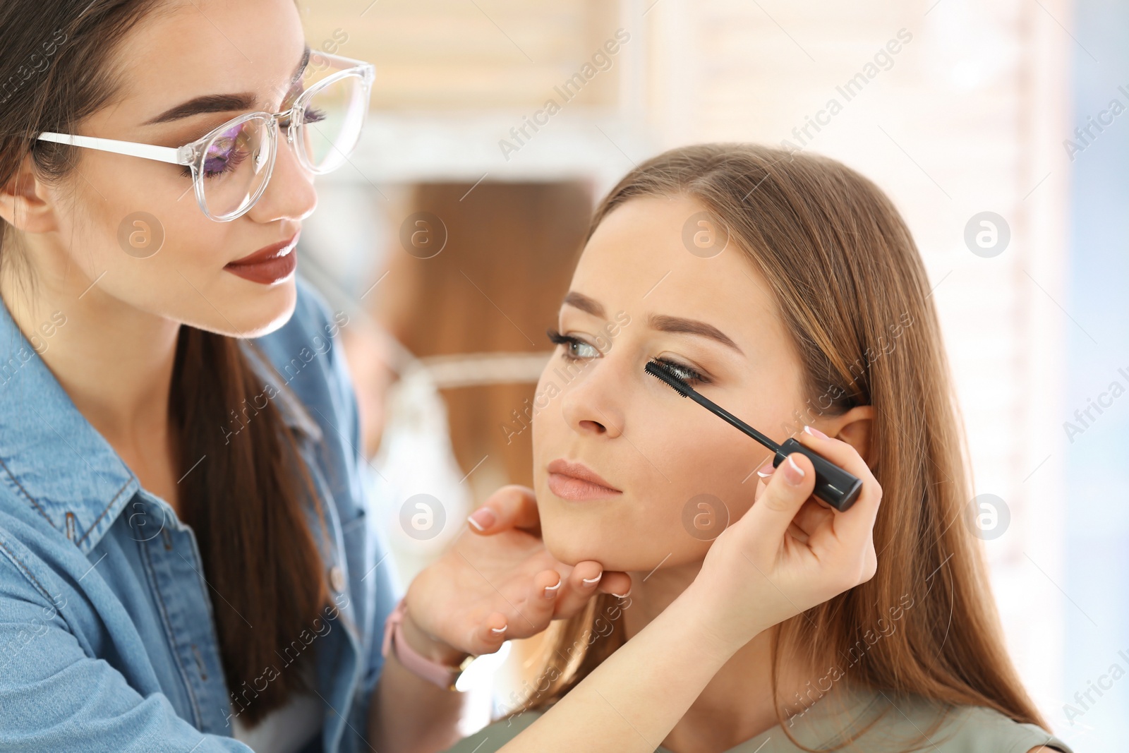 Professional visage artist applying makeup on woman's face in salon Photo of Professional visage artist applying makeup on woman's face in salon