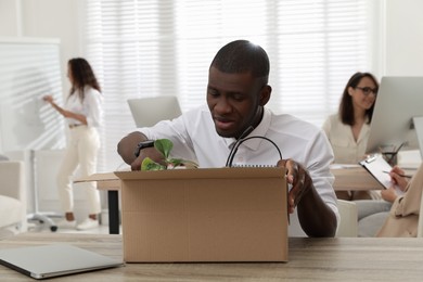 Photo of New coworker unpacking box with personal items at workplace in office