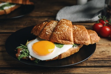 Delicious croissant with arugula and fried egg on wooden table, closeup Photo of Delicious croissant with arugula and fried egg on wooden table, closeup