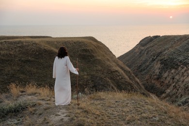 Jesus Christ on hills at sunset, back view. Space for text Photo of Jesus Christ on hills at sunset, back view. Space for text