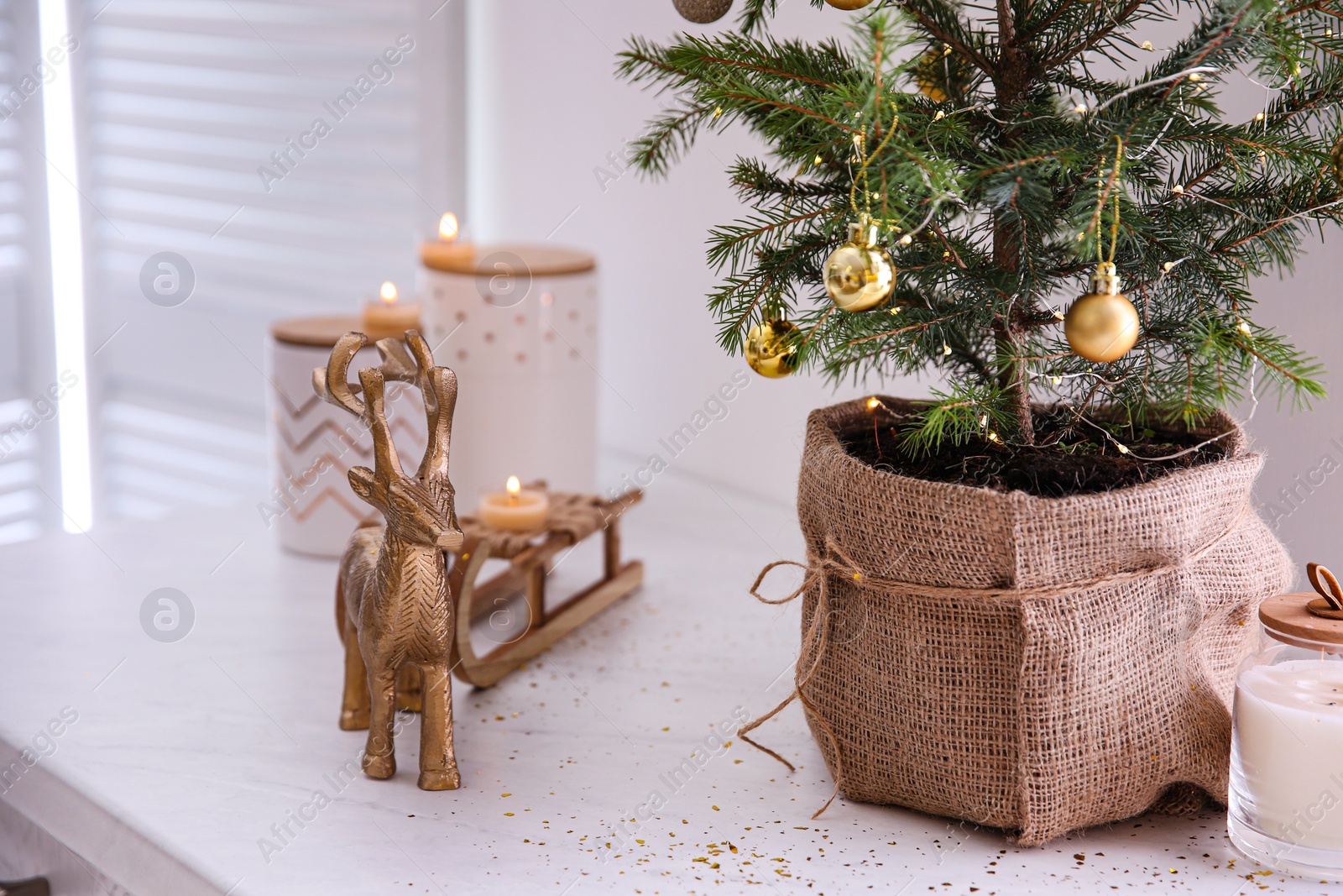 Small decorated Christmas tree and reindeer figure on countertop in kitchen, closeup Photo of Small decorated Christmas tree and reindeer figure on countertop in kitchen, closeup