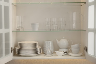 Cabinet with crockery and glassware. Order in kitchen Photo of Cabinet with crockery and glassware. Order in kitchen