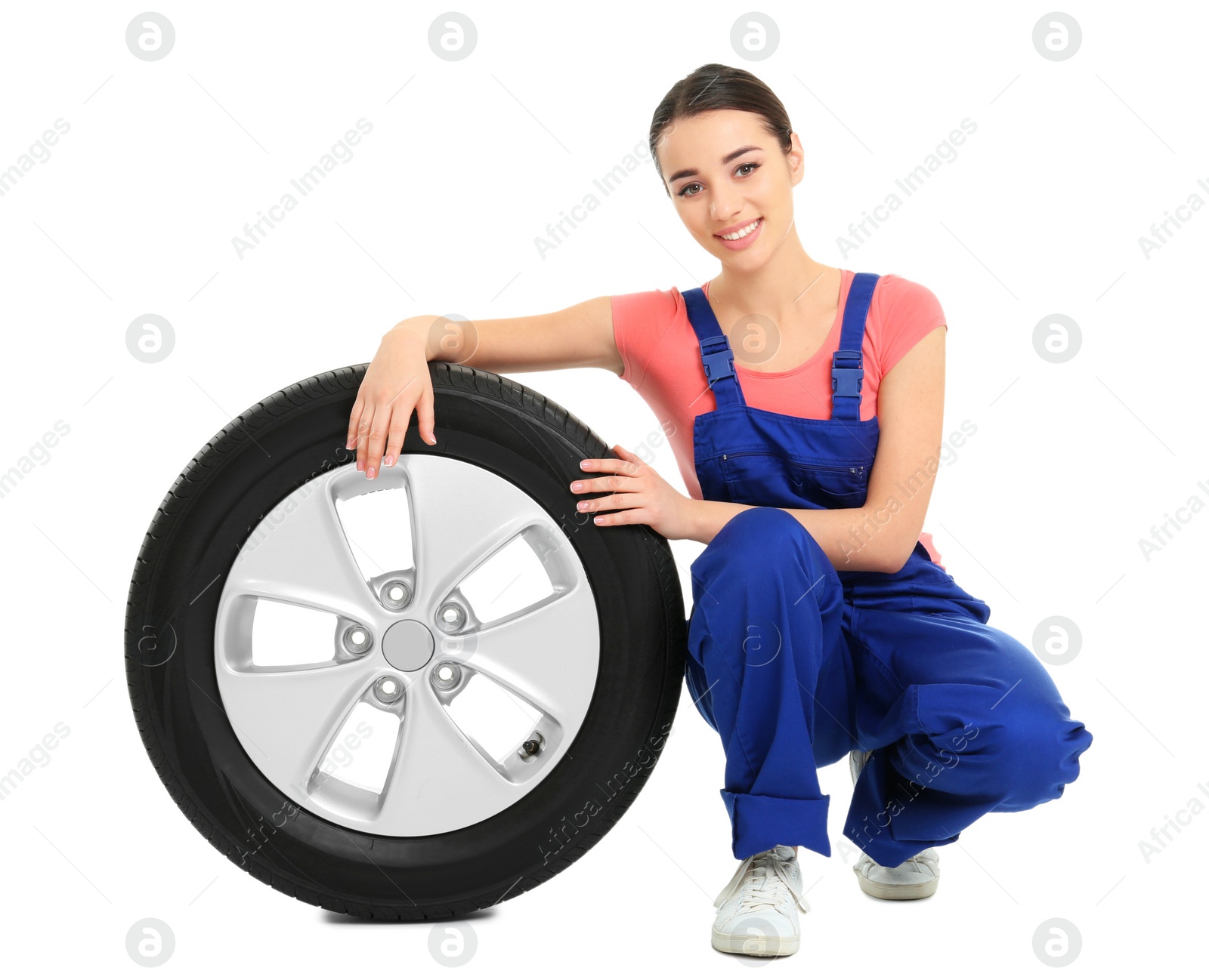 Female mechanic in uniform with car tire on white background Photo of Female mechanic in uniform with car tire on white background