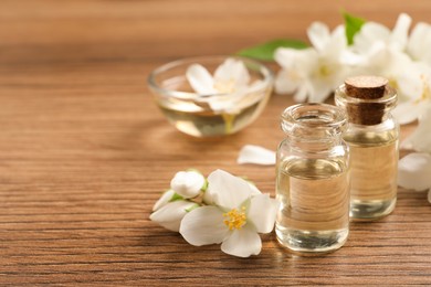 Jasmine essential oil and fresh flowers on wooden table, space for text Photo of Jasmine essential oil and fresh flowers on wooden table, space for text