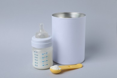 Blank can of powdered infant formula with scoop and feeding bottle on light grey background. Baby milk Photo of Blank can of powdered infant formula with scoop and feeding bottle on light grey background. Baby milk